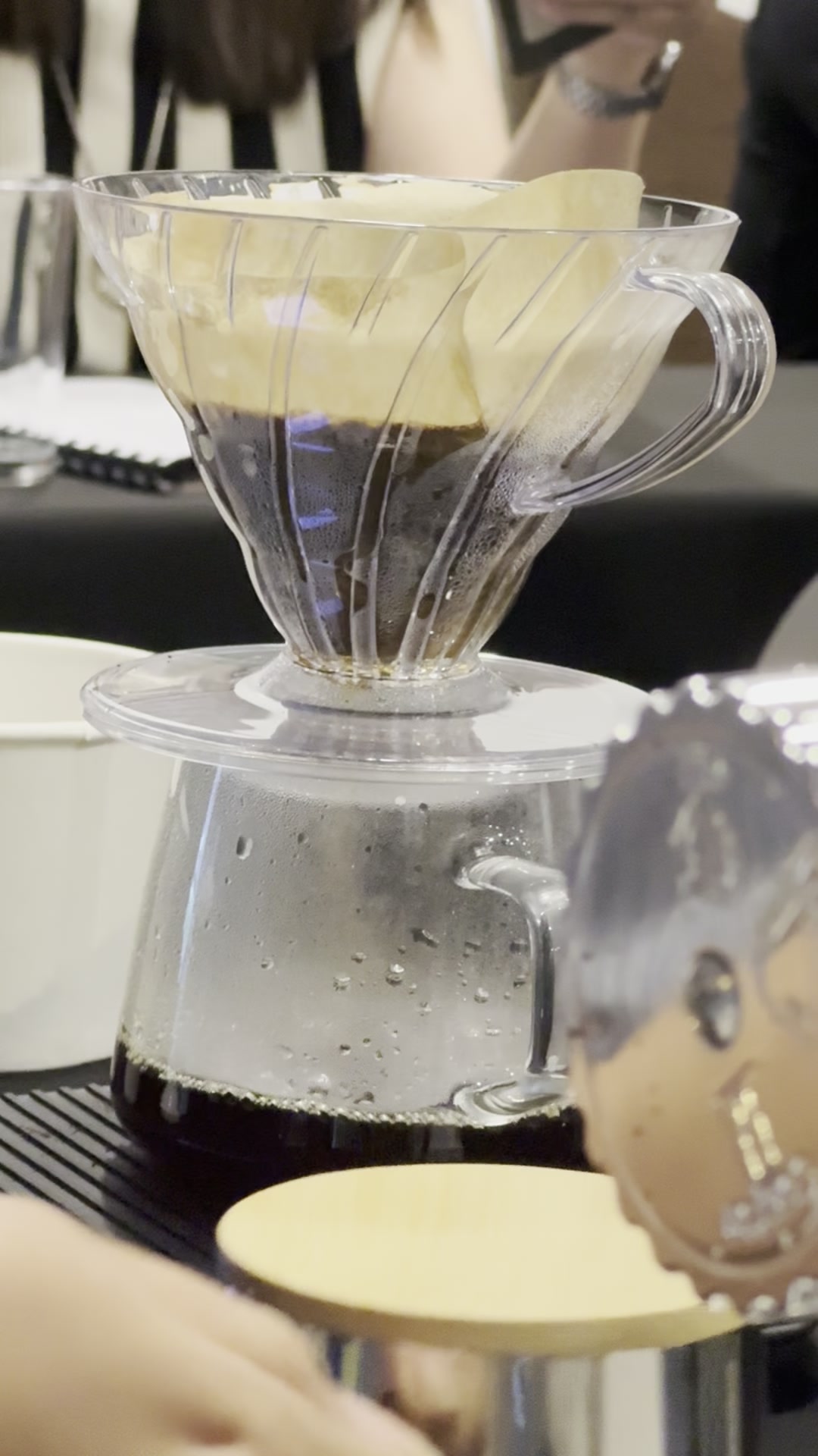 Coffee dripping through a pourover into a glass server during a class