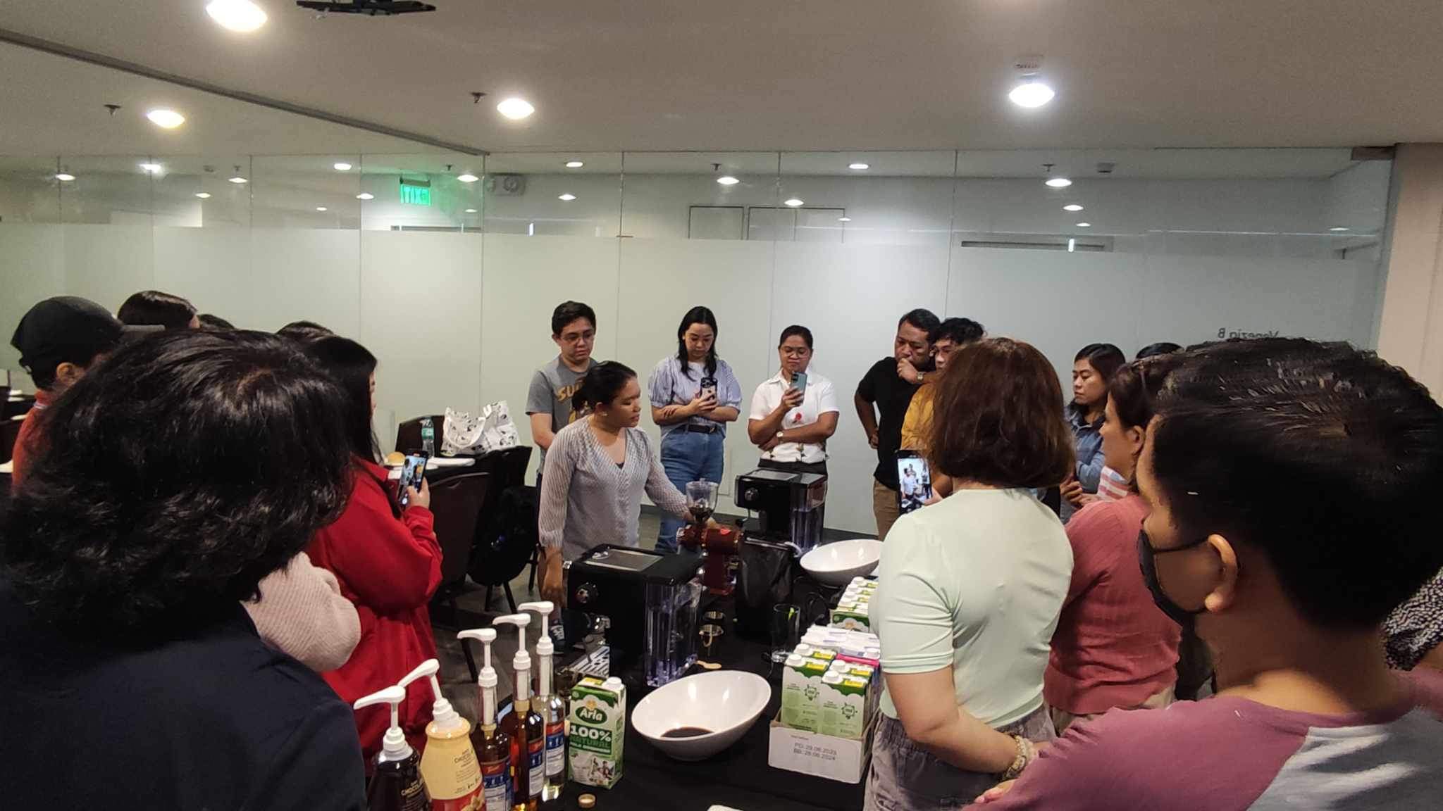 A full class gathered around the demo bar during a session